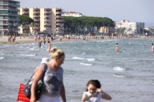 Turistes en primer terme, amb la platja de la Pineda de fons.